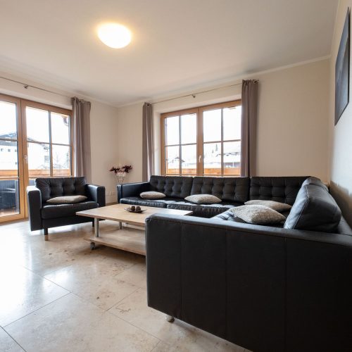 Wohnzimmer mit schwarzem Sofa in Ferienwohnung in Garmisch-Partenkirchen