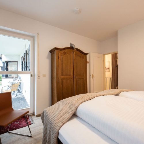 Doppelbett und Stuhl in Ferienwohnung in Garmisch-Partenkirchen