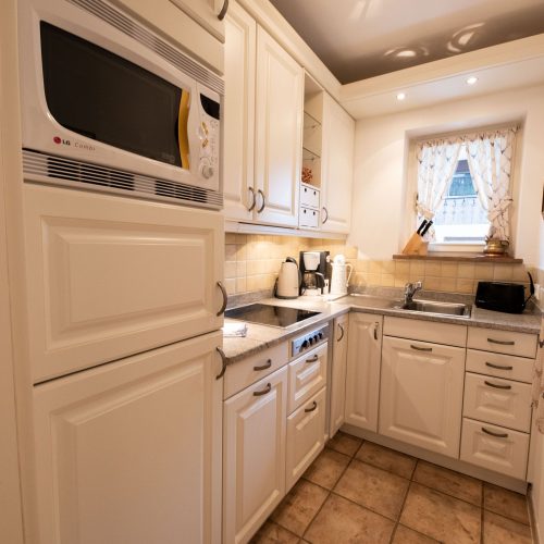 Küche in weiß mit Mikrowelle in Ferienwohnung in Garmisch-Partenkirchen