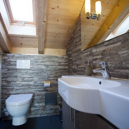 Badezimmer mit Steinwand und Waschbecken in Ferienwohnung in Garmisch-Partenkirchen