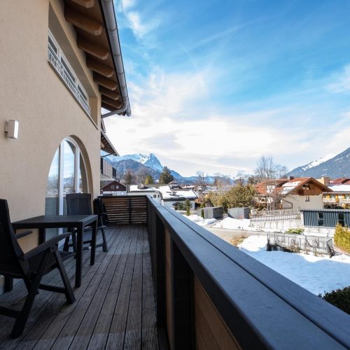 Balkon mit Aussicht auf die Berge und Sitzmöglichkeiten mit einem kleinen Tisch in Ferienwohnung in Garmisch-Partenkirchen
