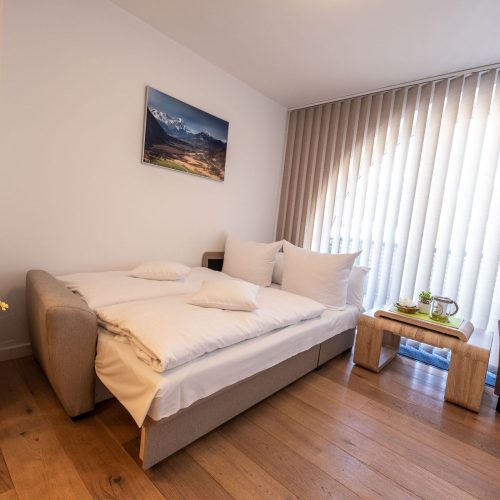 Schlafsofa mit einem Landschaftsbild und einem kleinen Tisch in Ferienwohnung in Garmisch-Partenkirchen