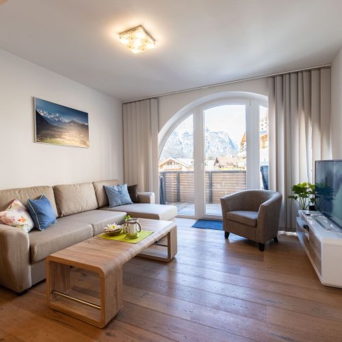 Wohnzimmer mit einem weißen Sideboard mit Fernseher in Ferienwohnung in Garmisch-Partenkirchen