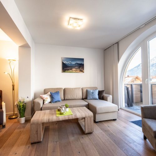 Wohnzimmer mit einem Sessel einem Sofa und einen tollen Ausblick auf die Berge in Ferienwohnung in Garmisch-Partenkirchen