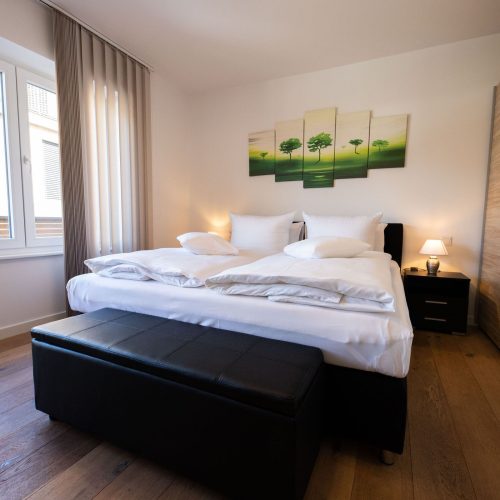 Doppelbett mit einem grünen Bild an der Wand und Nachtischen in Ferienwohnung in Garmisch-Partenkirchen