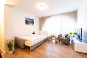 Schlafsofa und ein Sessel mit Fernseher auf einem Sideboard in Ferienwohnung in Garmisch-Partenkirchen