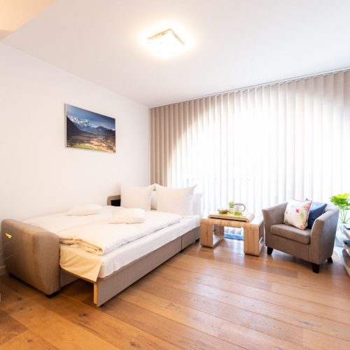 Schlafsofa und ein Sessel mit Fernseher auf einem Sideboard in Ferienwohnung in Garmisch-Partenkirchen