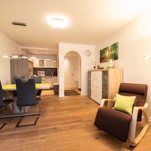 Wohnbereich mit einem kleinen Esstisch, einem Sessel, und einer offenen Küche in Ferienwohnung in Garmisch-Partenkirchen