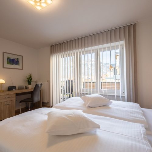 Doppelbett mit einem Schreibtisch in Ferienwohnung in Garmisch-Partenkirchen