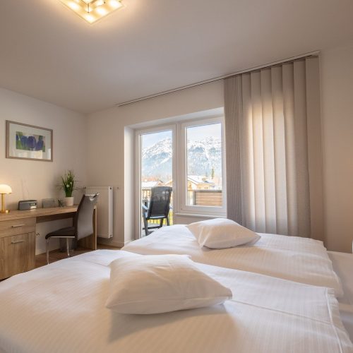 geräumiges Schlafzimmer mit einem Doppelbett und Schreibtisch, außerdem mit einem tollen Ausblick in Ferienwohnung in Garmisch-Partenkirchen