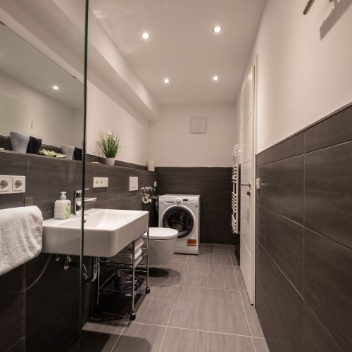 Badezimmer mit einem großen Spiegel in Ferienwohnung in Garmisch-Partenkirchen