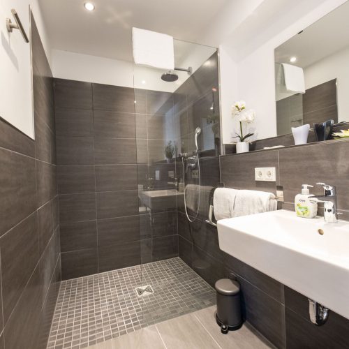 Badezimmer mit gefliester Wand und helleren Bodenfliesen in Ferienwohnung in Garmisch-Partenkirchen