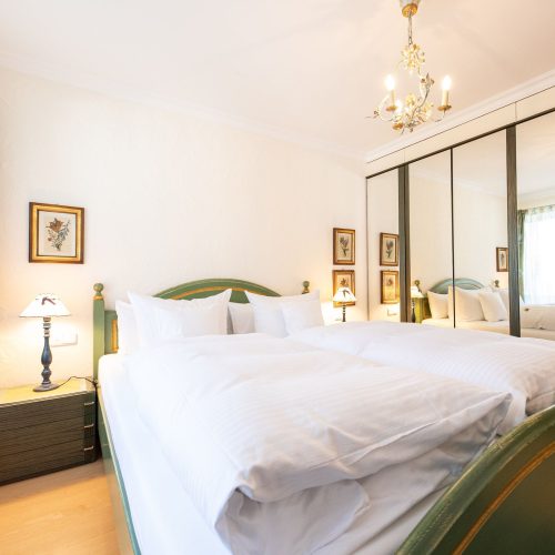 Doppelbett grün und Spiegel in Ferienwohnung in Garmisch-Partenkirchen