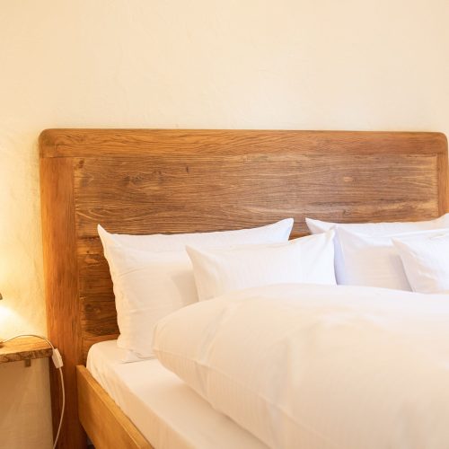 Weißes Bett mit Holzrückwand in Ferienwohnung in Garmisch-Partenkirchen