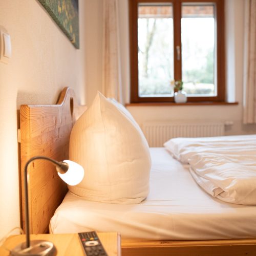 Doppelbett mit Nachttisch und Lampe in Ferienwohnung in Garmisch-Partenkirchen