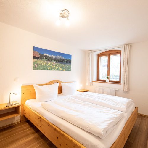 Doppelbett mit Nachttisch und Bild in Ferienwohnung in Garmisch-Partenkirchen