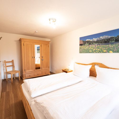 Doppelbettzimmer mit Kleiderschrank und Bild von einer Wiese in Ferienwohnung in Garmisch-Partenkirchen