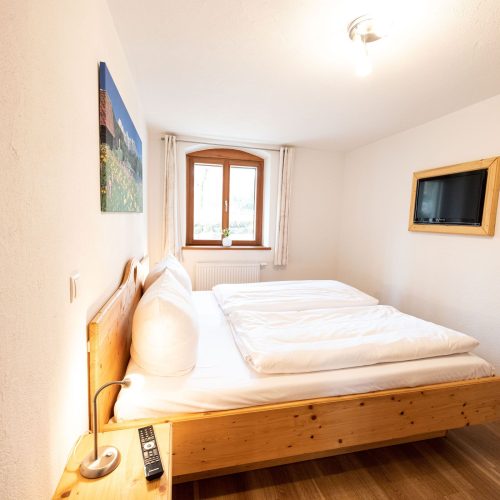 Doppelbettzimmer mit Fernseher und Fenster in Ferienwohnung in Garmisch-Partenkirchen