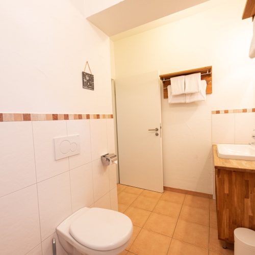 Badezimmer mit einer Holz-Optik Kommode mit weißem Waschbecken in Ferienwohnung in Garmisch-Partenkirchen