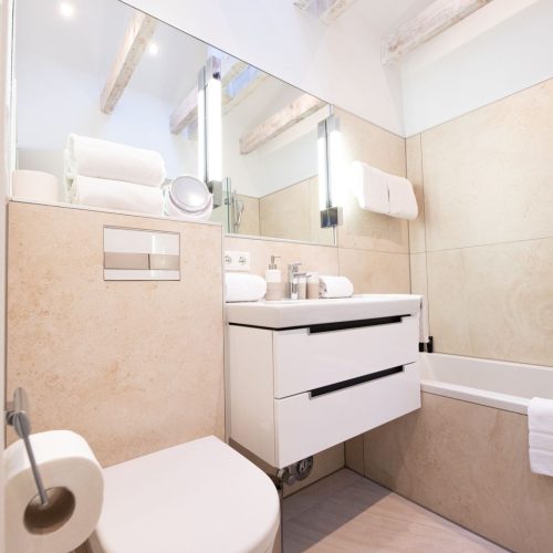 Badezimmer mit weißem Waschbecken und großen Spiegel in Ferienwohnung in Garmisch-Partenkirchen