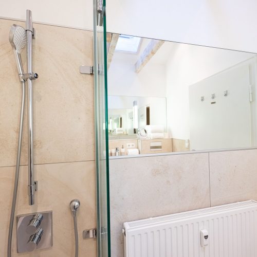 Badezimmer mit Spiegel und Dusche in Ferienwohnung in Garmisch-Partenkirchen