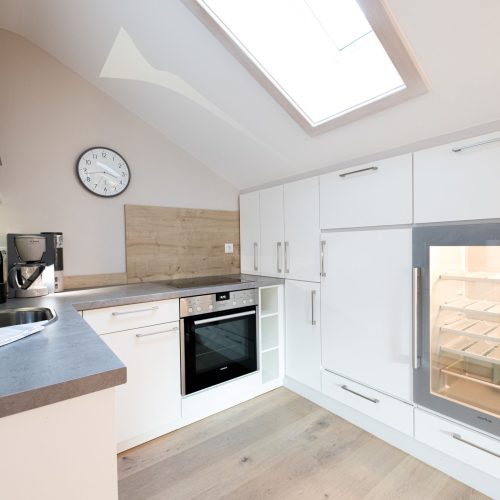 weiße Küche mit Wanduhr in Ferienwohnung in Garmisch-Partenkirchen