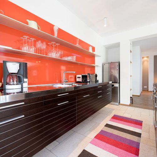 Küche mit roter Wand und verschiedenen Küchengeräten in Ferienwohnung in Garmisch-Partenkirchen