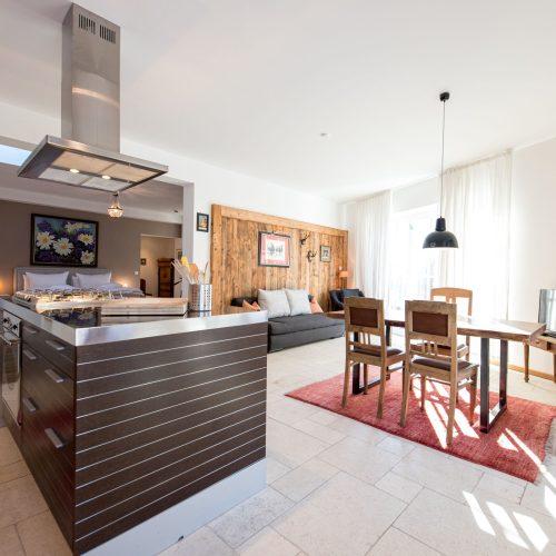 offene Küche mit Kücheninsel und Essbereich mit Sofa in Ferienwohnung in Garmisch-Partenkirchen