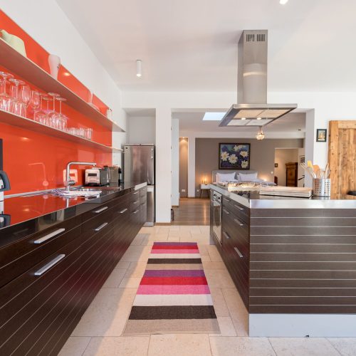 Küche mit Kücheninsel in rot und dunkel braun in Ferienwohnung in Garmisch-Partenkirchen