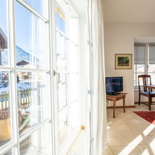 Wohnbereich mit Fernseher, Esstisch und Ausblick in Ferienwohnung in Garmisch-Partenkirchen