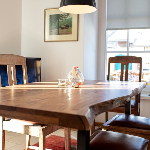 Esstisch in dunkler Holz-Optik mit dunklen Holz Stühlen und einer Vase in Ferienwohnung in Garmisch-Partenkirchen