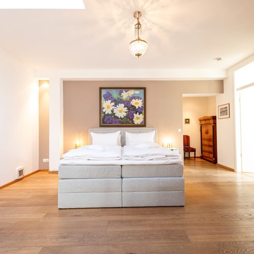 Doppelbett mit Bild von Blumen und Hängelampe in Ferienwohnung in Garmisch-Partenkirchen