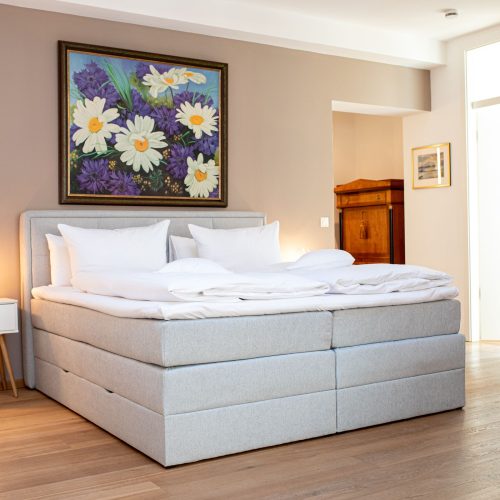 hell graues Doppelbett mit weißem Nachtschrank in Ferienwohnung in Garmisch-Partenkirchen