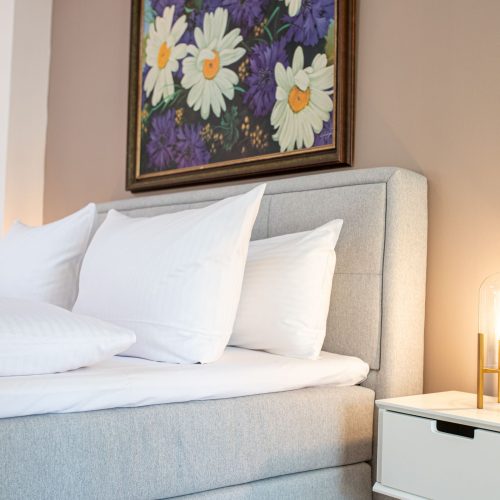 Schlafzimmer in hellgrau mit Beistelltischen mit Lampen und großem Blumen Bild in Ferienwohnung in Garmisch-Partenkirchen