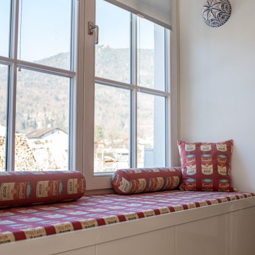Sitzmöglichkeit mit Kissen an einem großen Fenster mit Ausblick in Ferienwohnung in Garmisch-Partenkirchen