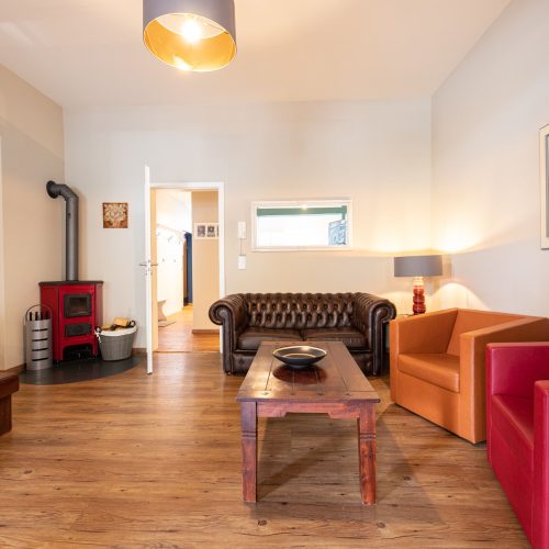 Wohnbereich mit rotem und orangem Sessel in Ferienwohnung in Garmisch-Partenkirchen