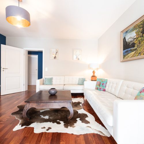 Wohnzimmer mit zwei Sofas und einem Kuh-Teppich in Ferienwohnung in Garmisch-Partenkirchen