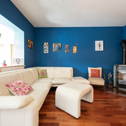 blaues Wohnzimmer mit einem weißen Sofa und einem weißen Hocker in Ferienwohnung in Garmisch-Partenkirchen