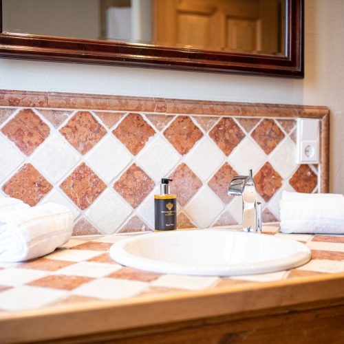 Badezimmer mit Waschbecken mit rot-weißen Fliesen in Ferienwohnung in Garmisch-Partenkirchen