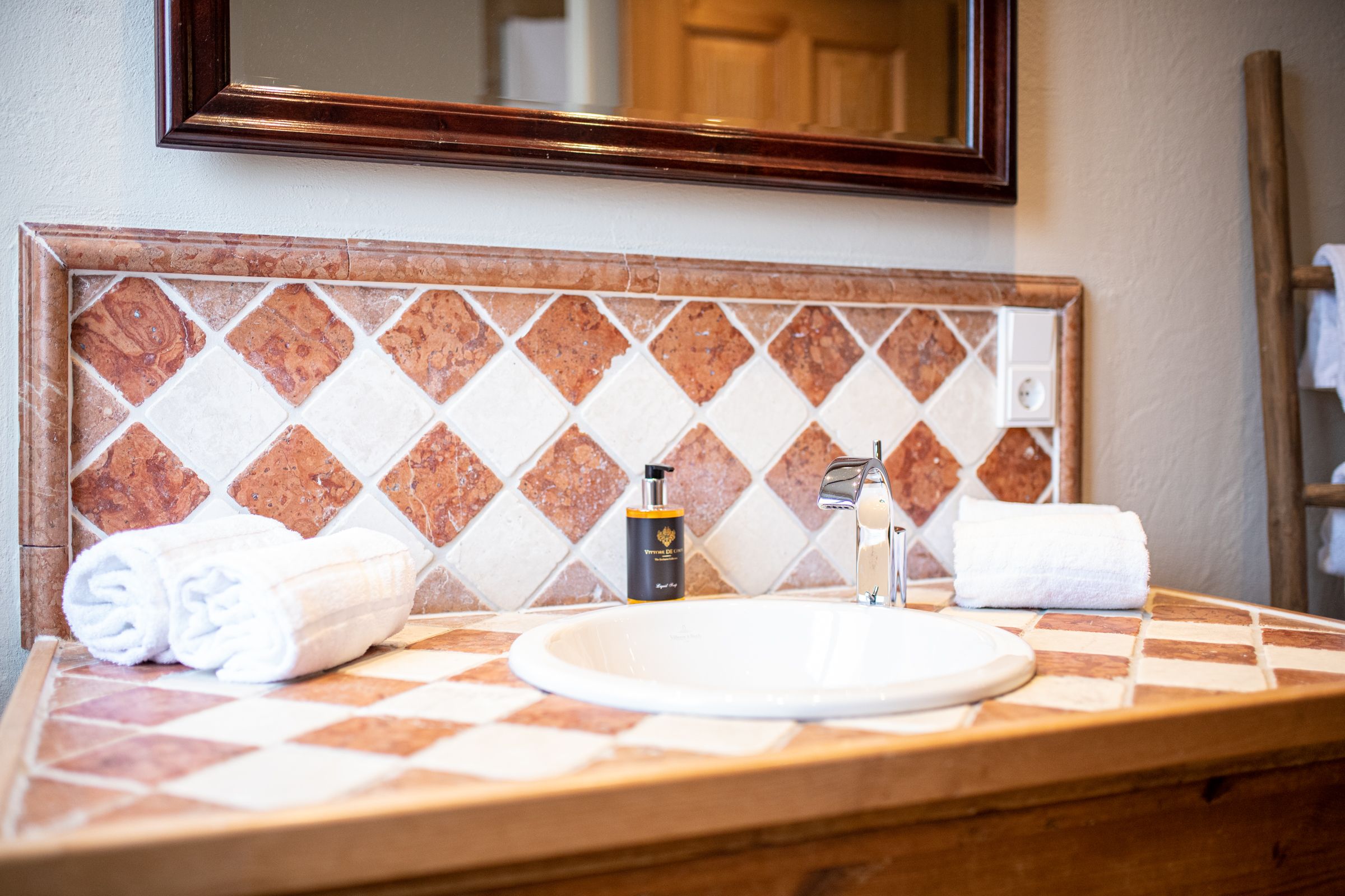 Badezimmer mit Waschbecken mit rot-weißen Fliesen in Ferienwohnung in Garmisch-Partenkirchen