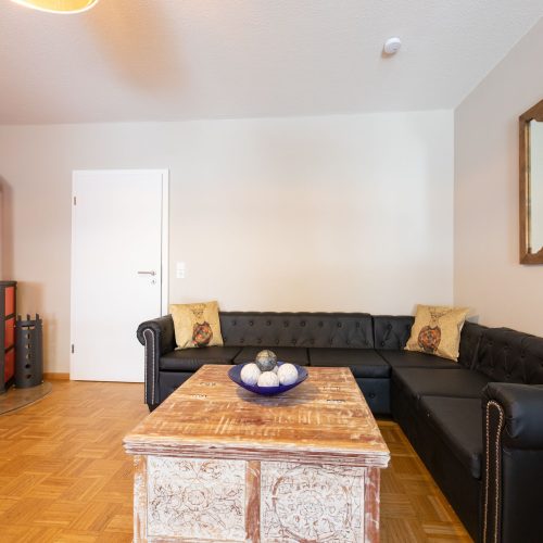 schwarzes Sofa mit einem großen Spiegel in Ferienwohnung in Garmisch-Partenkirchen