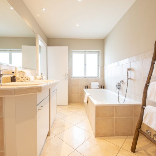 Badezimmer mit einem großen Spiegel und Badewanne in Ferienwohnung in Garmisch-Partenkirchen