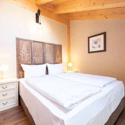 Doppelbett mit weißen Nachttischen in Ferienwohnung in Garmisch-Partenkirchen