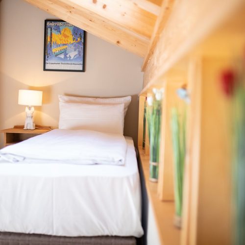 Einzelbett mit Nachttisch und Lampe in Ferienwohnung in Garmisch-Partenkirchen