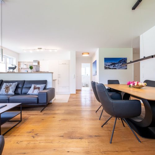 offener Wohnbereich mit einer schwarzen Couch in Ferienwohnung in Garmisch-Partenkirchen