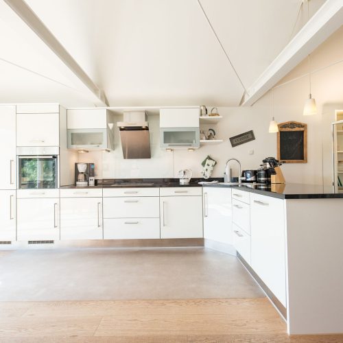 weiße offene Küche mit schwarzer Arbeitsfläche in Ferienwohnung in Garmisch-Partenkirchen