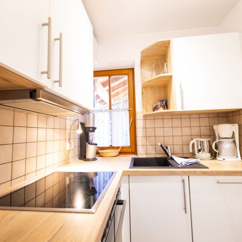 Küche mit beigen Fliesen und Herdplatte in Ferienwohnung in Garmisch-Partenkirchen