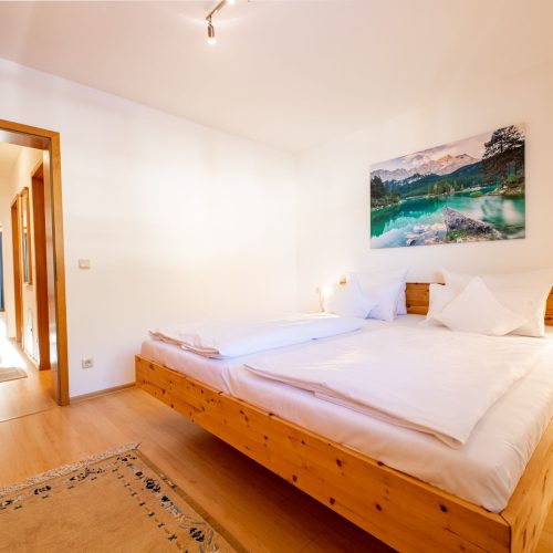 Schlafbereich in hell braun mit einem großen Bett in Ferienwohnung in Garmisch-Partenkirchen