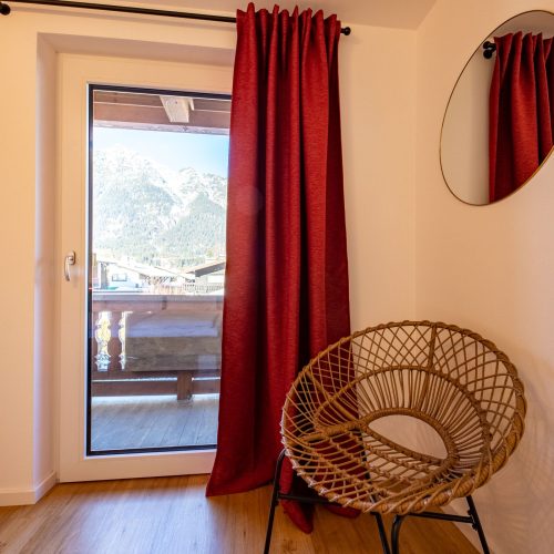 Schlafzimmer mit roter Gardine in Ferienwohnung in Garmisch-Partenkirchen