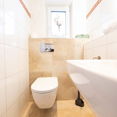 Badezimmer mit weißen und Sandfarbenden Fliesen in Ferienwohnung in Garmisch-Partenkirchen